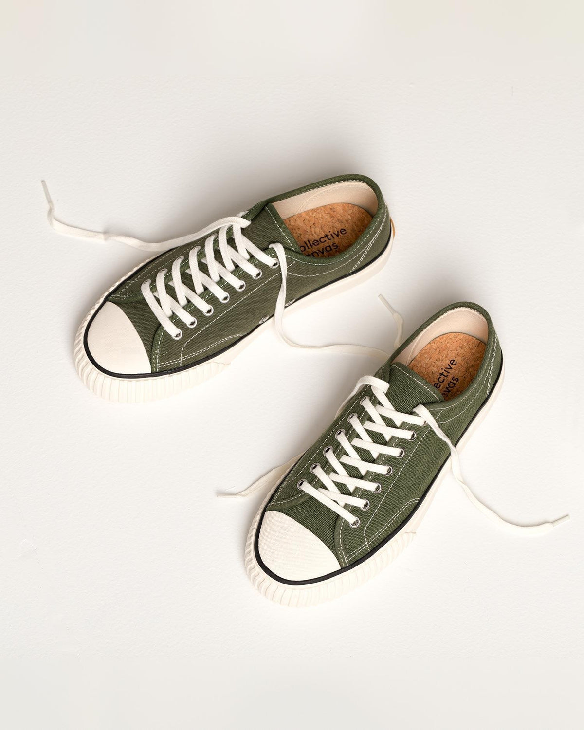 Pair of Straat Hemp Olive trainers laid on white with loose laces, showing cork insoles