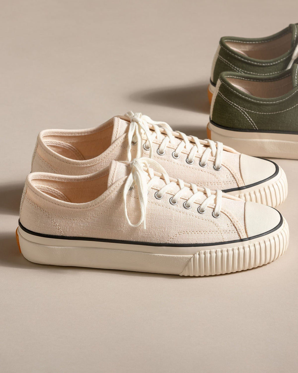 Straat Hemp Natural/Black trainers on a beige backdrop with an olive pair behind