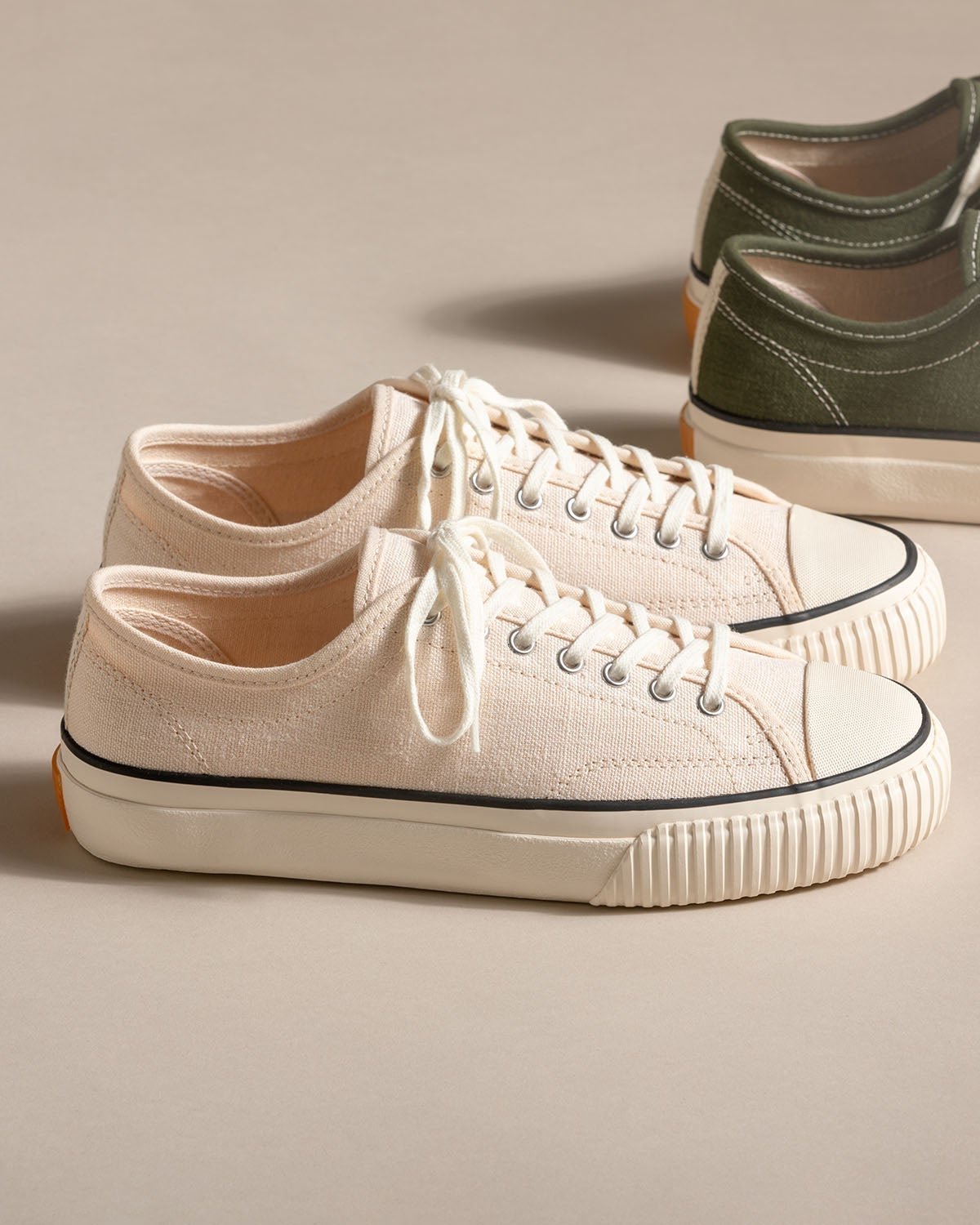 Straat Hemp Natural/Black trainers on a beige backdrop with an olive pair behind