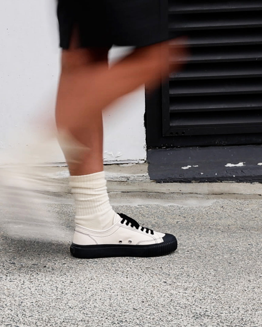 Mid-stride in Buddy x CC Hemp Off-White/Black trainers and white socks, with motion blur
