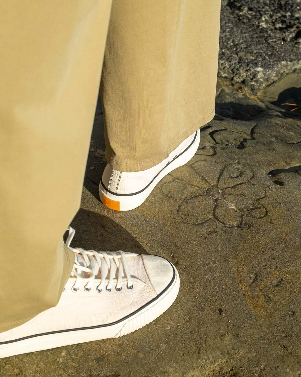 Wearing Straat Hemp Natural/Black trainers with wide-leg khaki trousers on sunlit rock