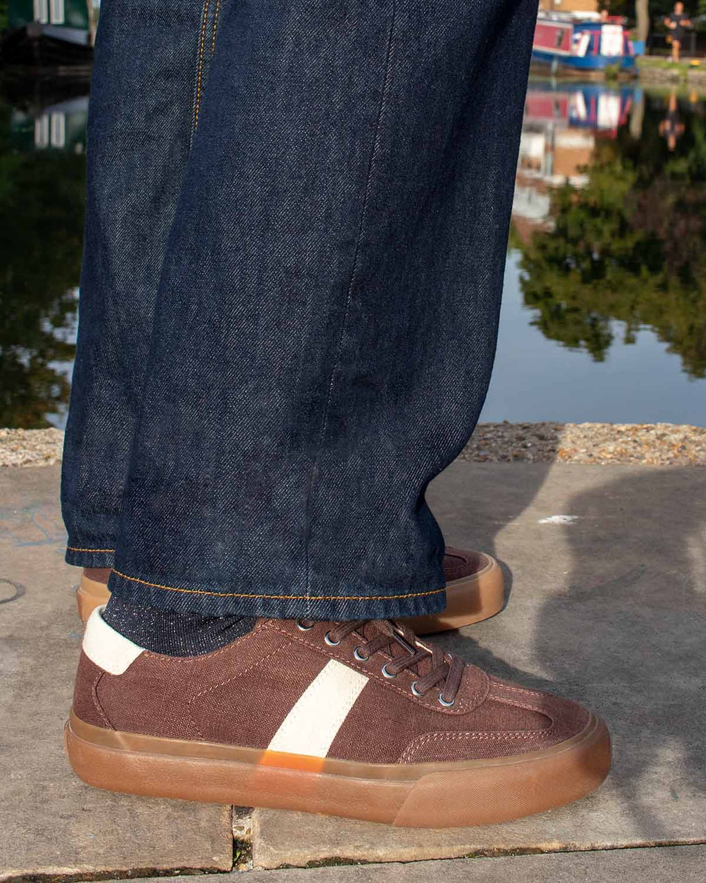 Veld Hemp Coffee/Ecru trainers worn with dark raw denim beside a canal