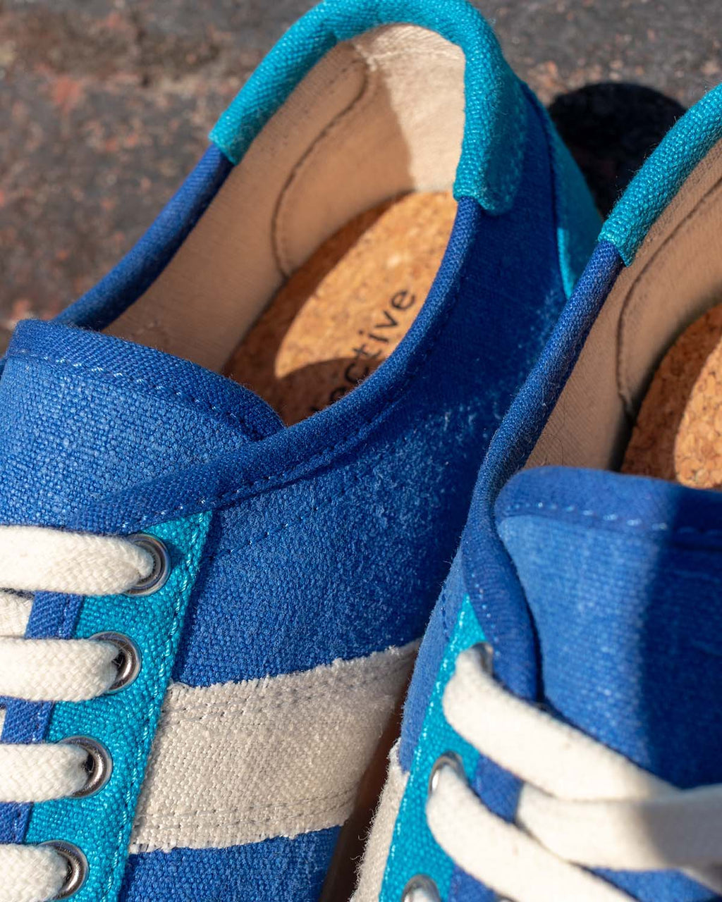 Close-up of Looper Hemp Blue eyelets, ecru stripe, white laces and cork insole