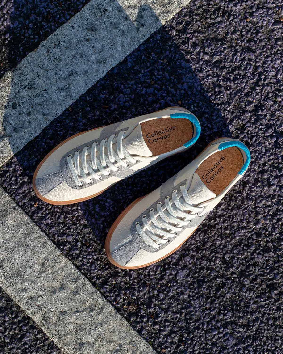 Pair of Looper Hemp Ecru/Grey trainers lying on dark asphalt beside a painted white line