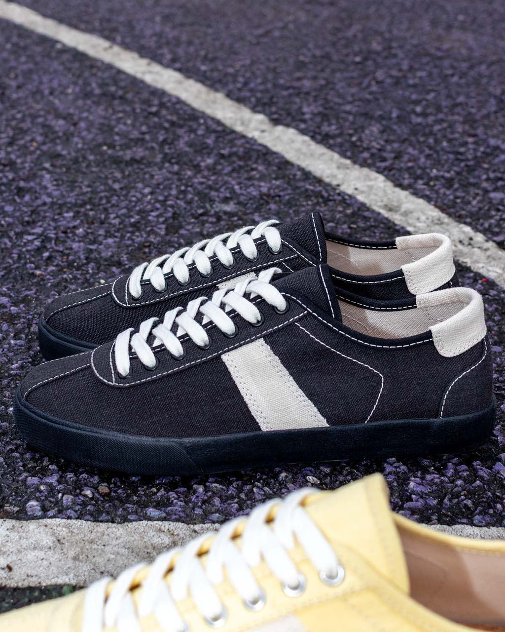 Looper Hemp Black/White Stitch trainers on a court surface beside a white line, a Butter/Ecru toe in view