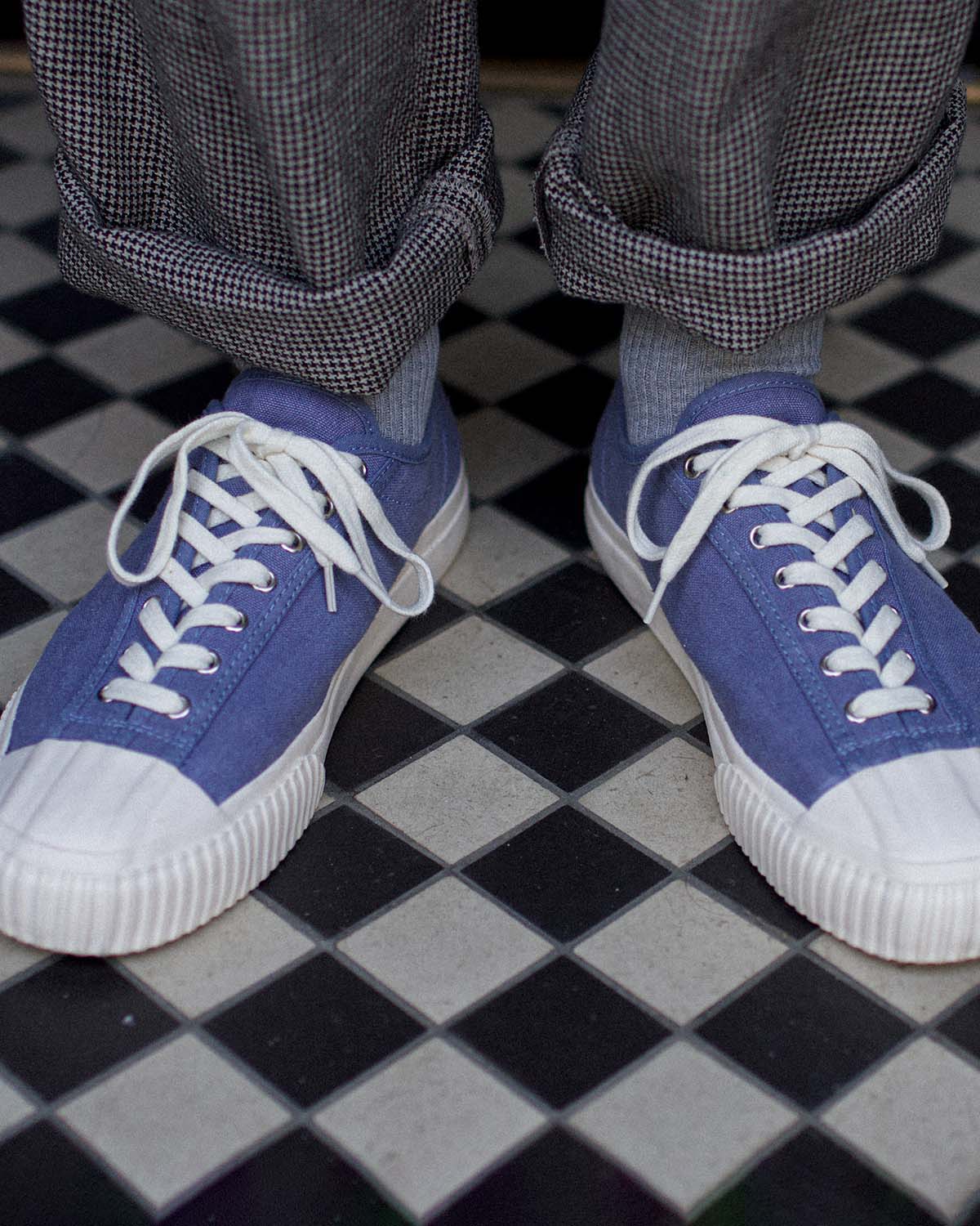 Wearing CC x Original Fibres Stonewash trainers with grey socks and cuffed check trousers on chequered tiles