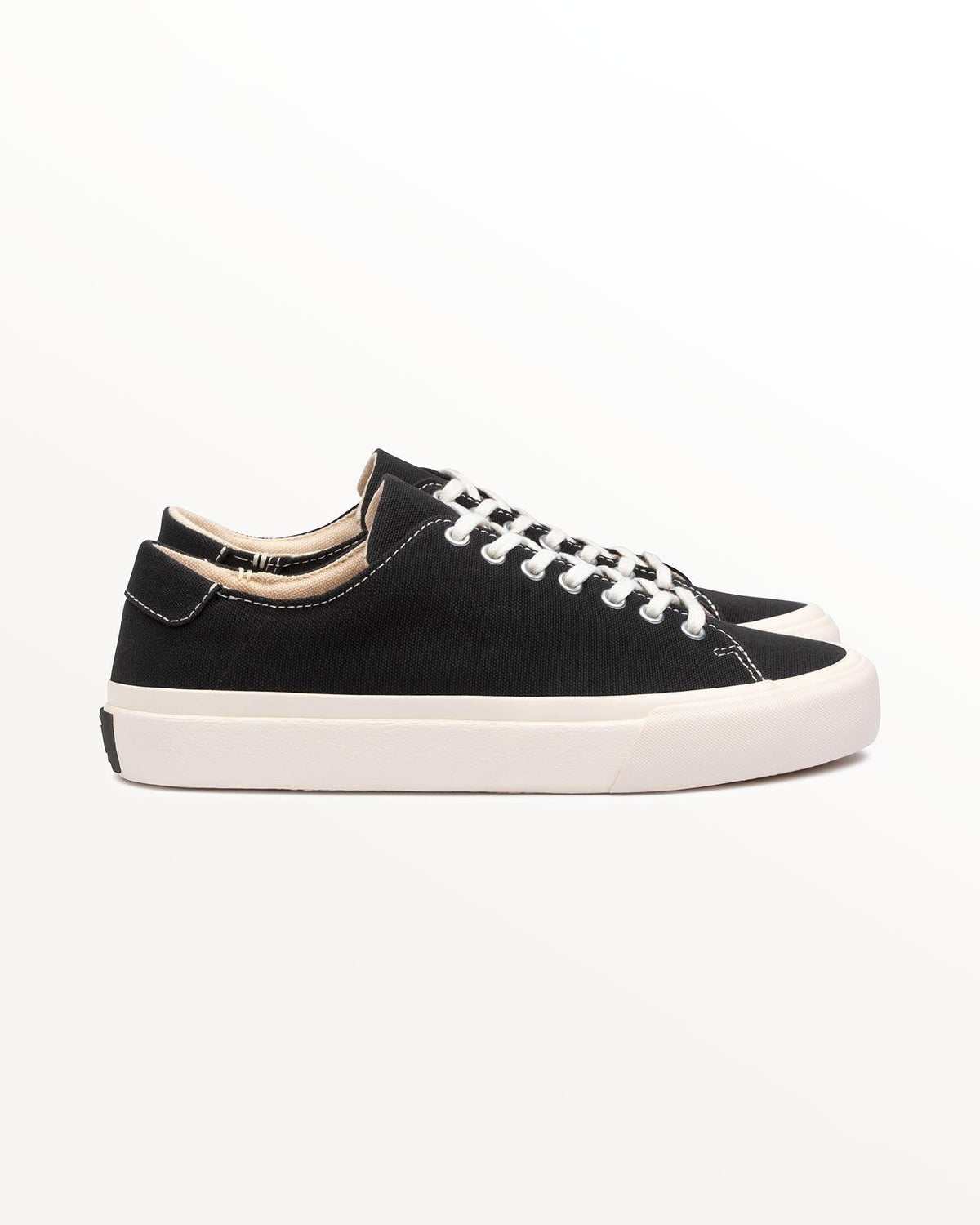 Baan Black/White trainer, side view of black organic cotton canvas on off-white rubber sole with black heel patch