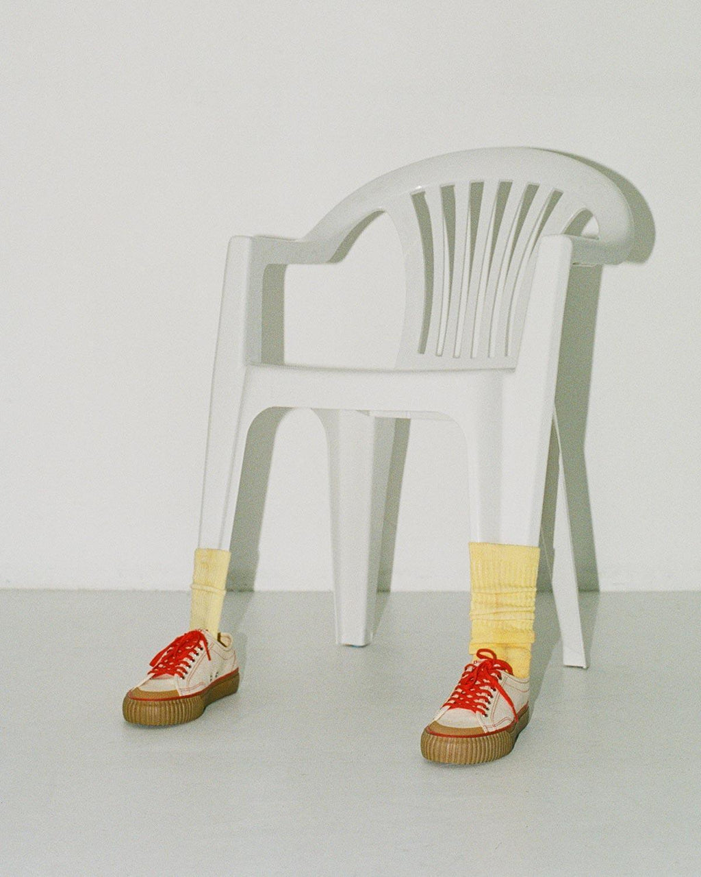 Buddy x CC Hemp Off-White/Red trainers with yellow socks in front of a white plastic chair