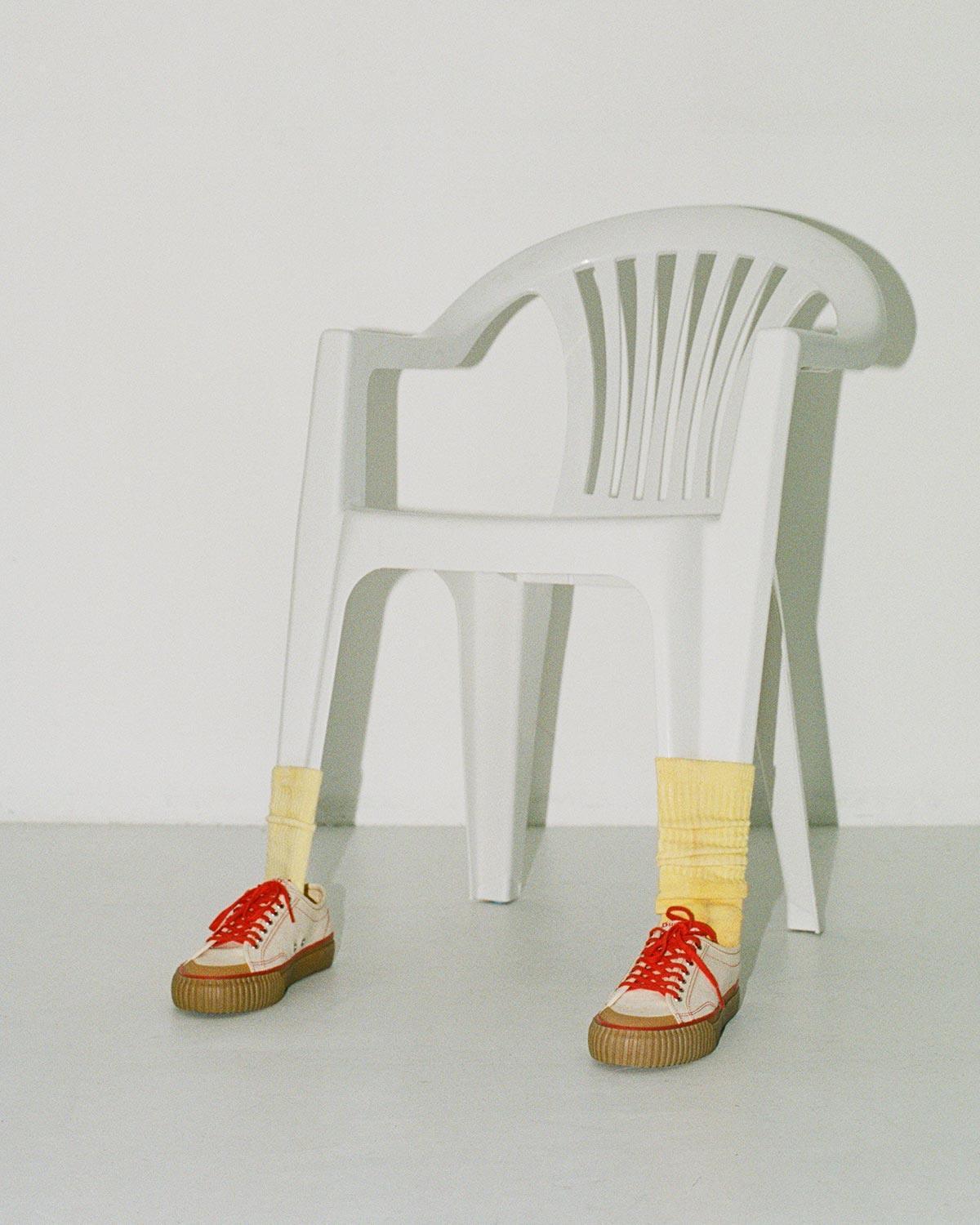Buddy x CC Hemp Off-White/Red trainers with yellow socks in front of a white plastic chair