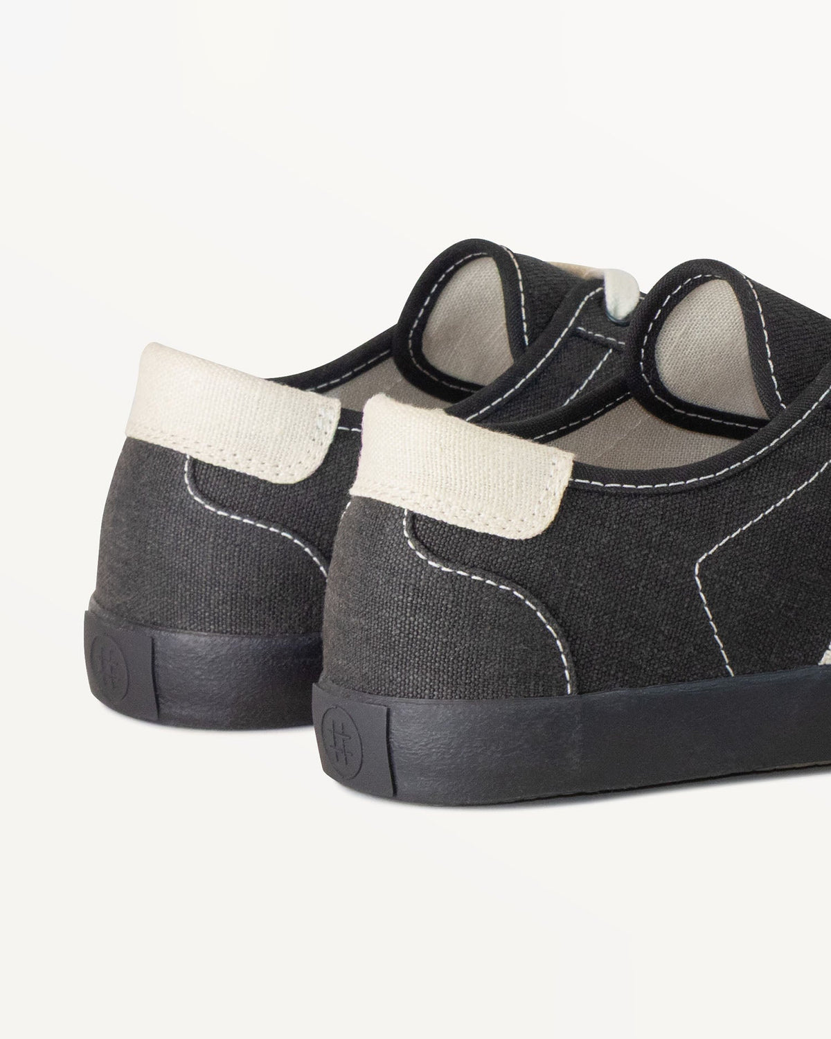 Close-up of Looper Black/White Stitch heel with ecru heel tab and embossed logo on the black rubber sole