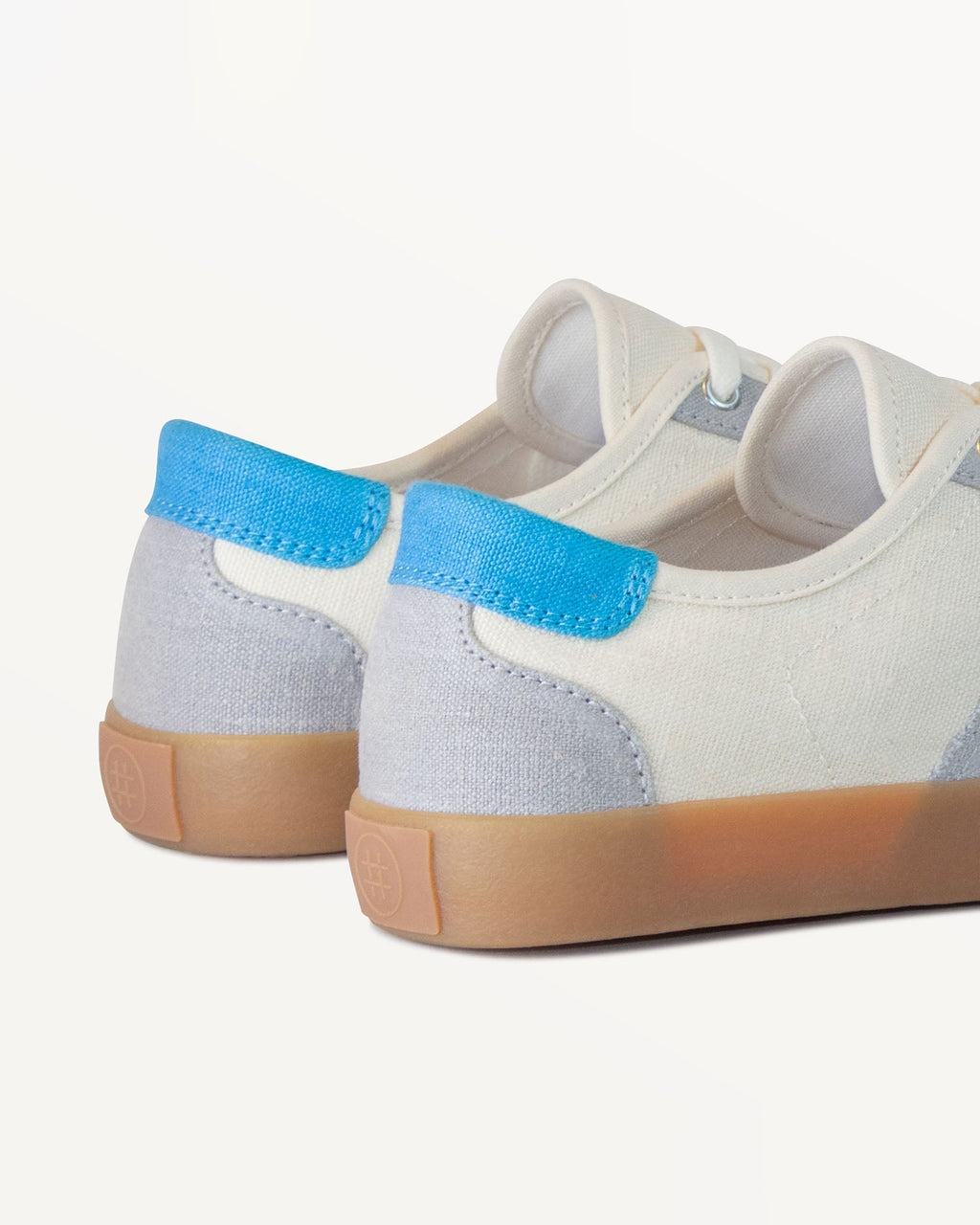 Close-up of Looper Ecru/Grey heel with blue heel tab and embossed logo on the natural gum rubber sole
